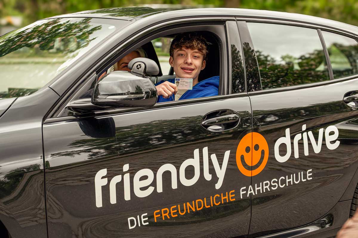 Glücklicher Fahrschüler im Friendly Drive Fahrschulauto in München nach bestandener Führerscheinprüfung.